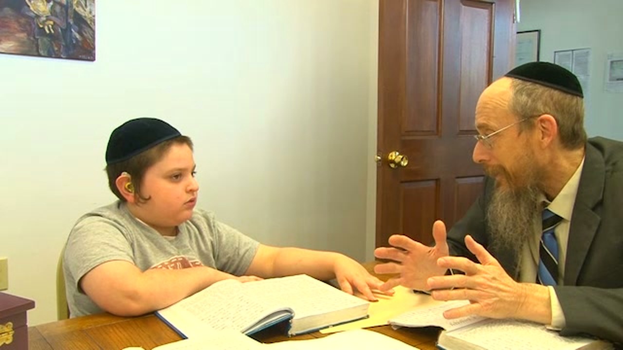 Rabbi Karp learns one-on-one with a boy, with open books on the table between them.